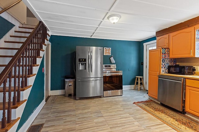 kitchen featuring stainless steel appliances, light countertops, visible vents, light wood-style flooring, and baseboards