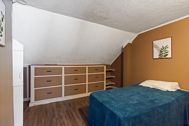 bedroom with lofted ceiling, a textured ceiling, and wood finished floors