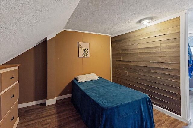 bedroom with wooden walls, baseboards, lofted ceiling, wood finished floors, and a textured ceiling