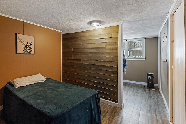 bedroom with a textured ceiling, baseboards, and wood finished floors