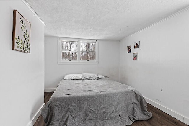 bedroom featuring a textured ceiling, baseboards, and wood finished floors