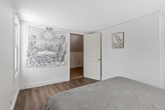 bedroom with a textured ceiling, baseboards, and wood finished floors