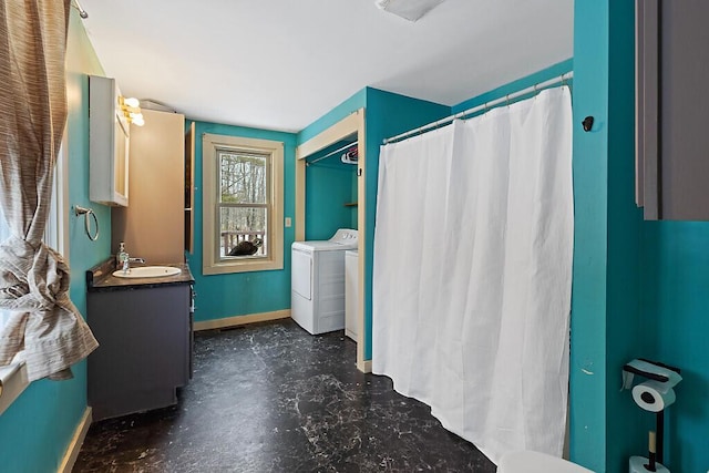 bathroom featuring curtained shower, concrete floors, vanity, baseboards, and washing machine and clothes dryer