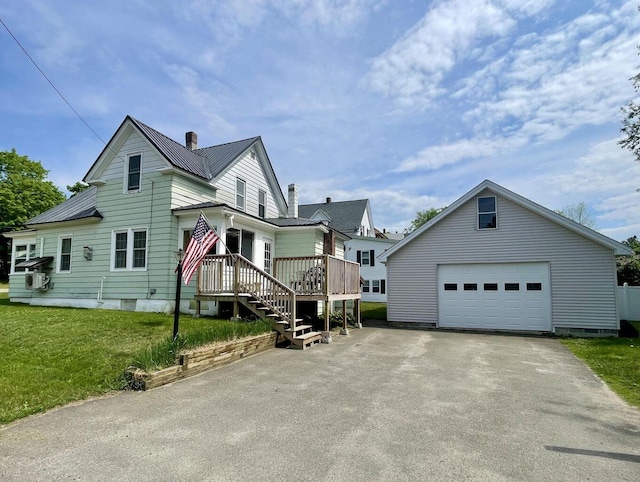 view of front of property with a detached garage, a chimney, a front yard, metal roof, and an outdoor structure