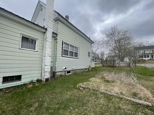 view of home's exterior featuring a lawn and a chimney