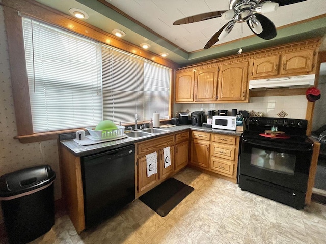 kitchen with under cabinet range hood, a sink, a ceiling fan, black appliances, and a tray ceiling