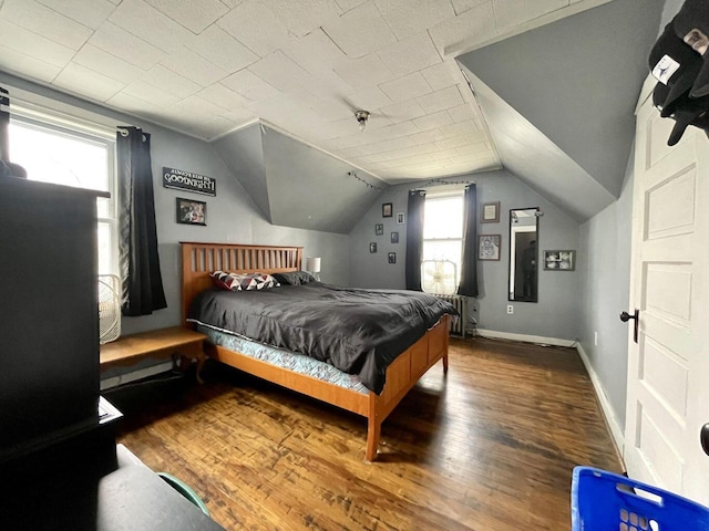 bedroom with baseboards, vaulted ceiling, and wood finished floors