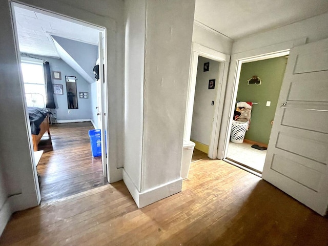 hallway with vaulted ceiling, baseboards, and wood finished floors