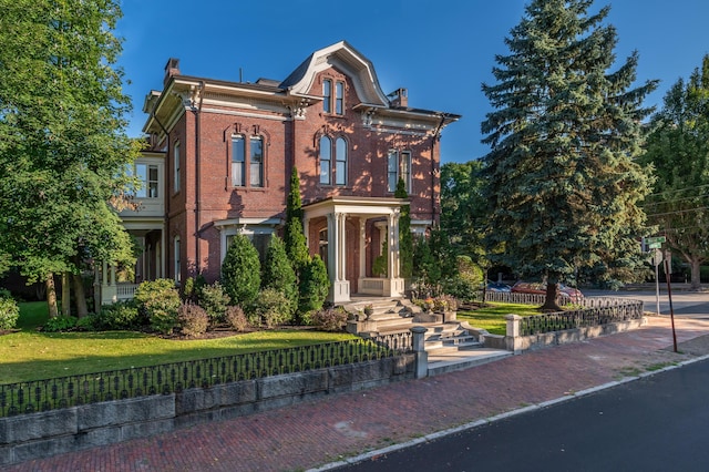 italianate house featuring brick siding, fence, a chimney, and a front lawn