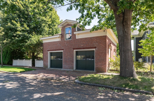 view of front of property featuring driveway, brick siding, and fence