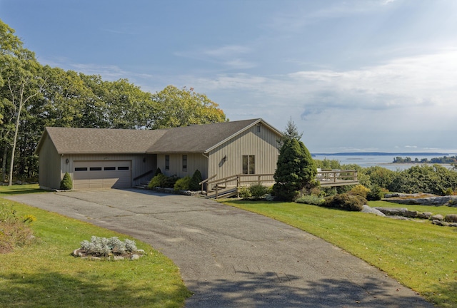 view of front of home featuring a garage, a front yard, a water view, and driveway