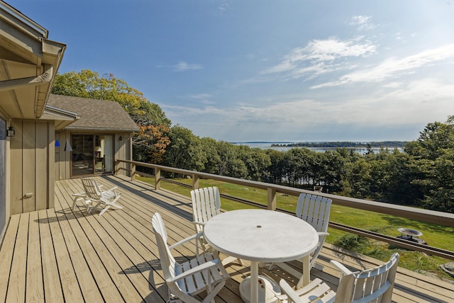 wooden terrace featuring outdoor dining space and a water view