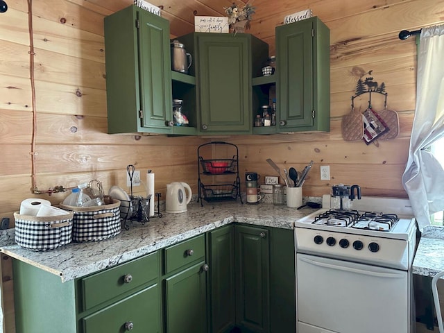 kitchen featuring white range with gas stovetop, wood walls, open shelves, and green cabinetry