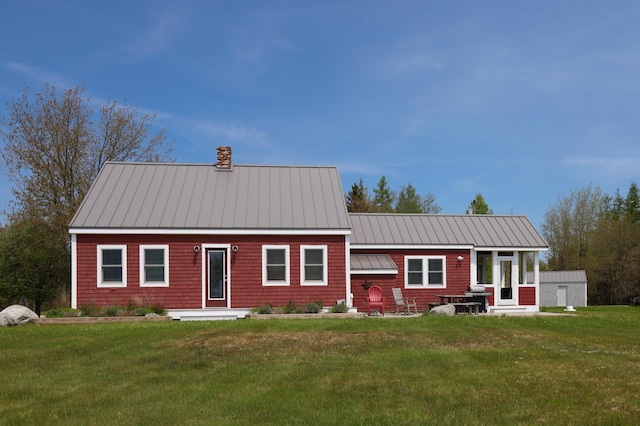 view of front of house featuring a chimney, a lawn, metal roof, and a standing seam roof