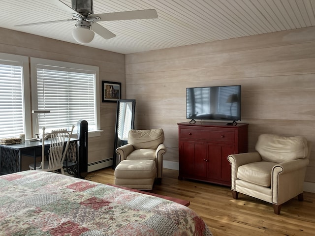 bedroom with a baseboard heating unit, a ceiling fan, and light wood-type flooring