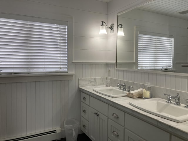 bathroom with a baseboard heating unit, double vanity, a wealth of natural light, and a sink