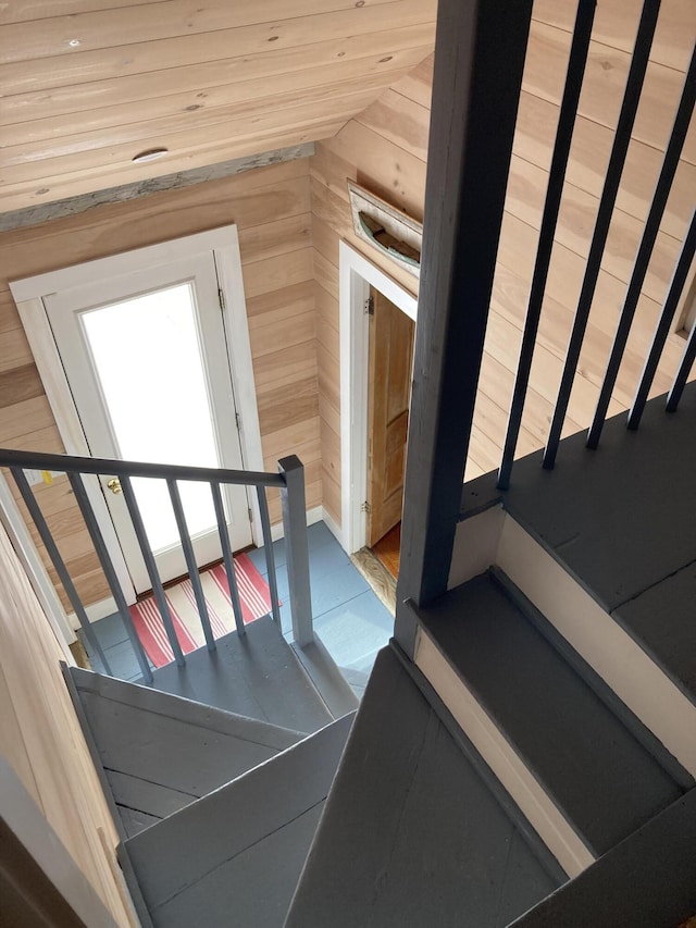 stairway with vaulted ceiling and wooden walls