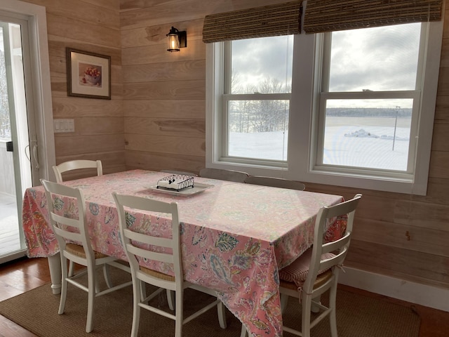 dining space with wood walls, baseboards, and wood finished floors