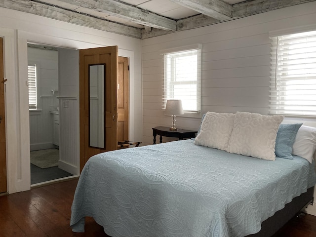 bedroom with beamed ceiling, wooden walls, and hardwood / wood-style flooring