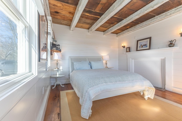 bedroom with beamed ceiling, wood ceiling, and wood finished floors