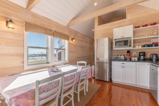 kitchen featuring lofted ceiling with beams, wooden walls, built in microwave, and freestanding refrigerator