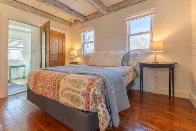 bedroom featuring beamed ceiling, wooden walls, and dark wood-style flooring