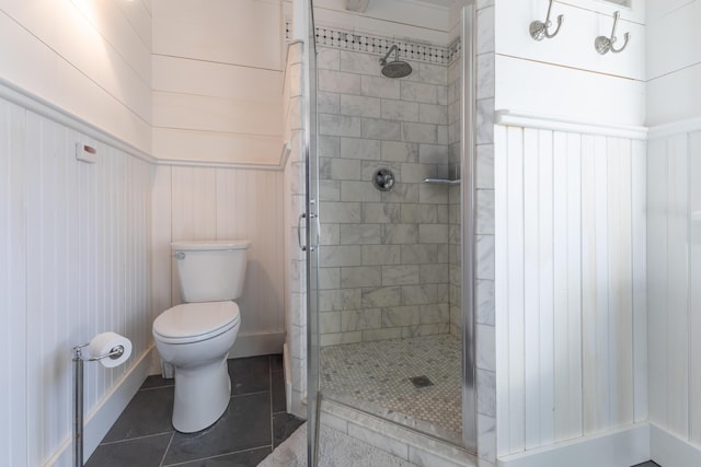 bathroom featuring tile patterned floors, toilet, and a stall shower