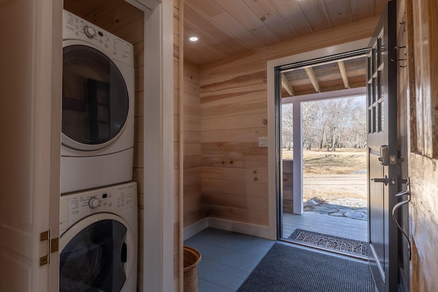 laundry room featuring stacked washer and dryer, wood ceiling, wood walls, and laundry area