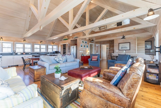 living room with beam ceiling, wooden walls, light wood finished floors, and high vaulted ceiling