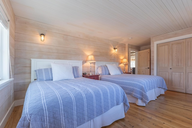 bedroom featuring a closet, multiple windows, wooden walls, and wood finished floors