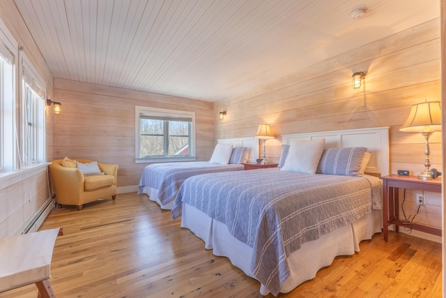 bedroom with a baseboard heating unit, wooden ceiling, and light wood finished floors