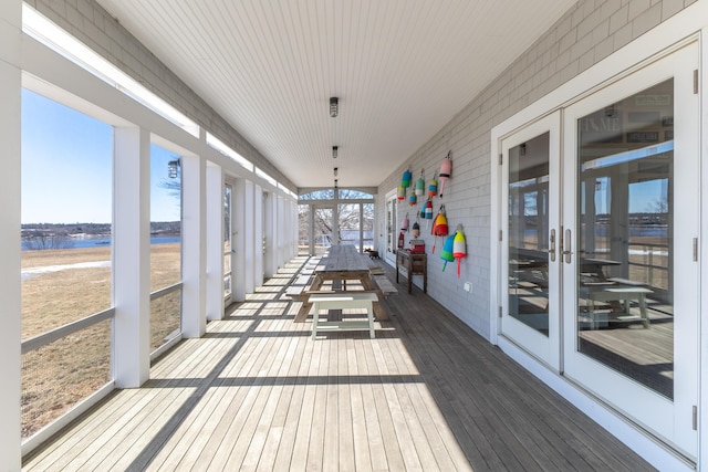 unfurnished sunroom with french doors and a water view