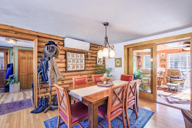 dining area featuring a wall unit AC, light wood-type flooring, and log walls