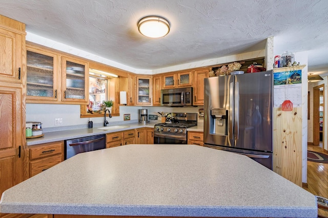 kitchen featuring light countertops, appliances with stainless steel finishes, a sink, and a center island