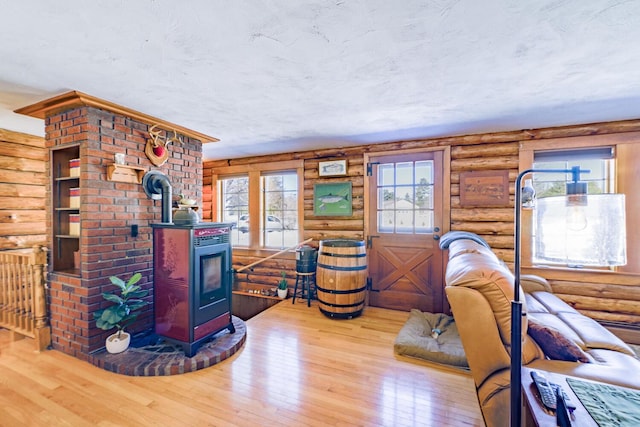 living room with a wood stove, rustic walls, and wood-type flooring