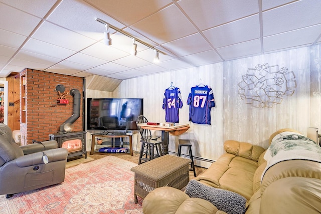 living room with a baseboard heating unit, a drop ceiling, a wood stove, and track lighting