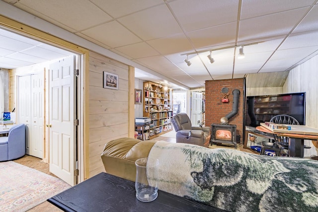 living room featuring wood walls, wood finished floors, a paneled ceiling, and track lighting