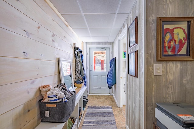 interior space featuring a drop ceiling and wooden walls