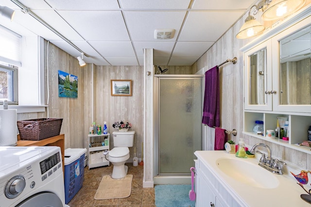 full bathroom featuring washer / clothes dryer, a drop ceiling, a shower stall, and wooden walls