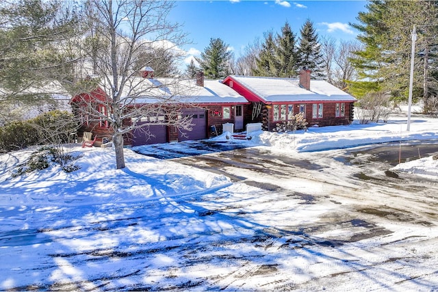 view of front of house featuring driveway, a chimney, and an attached garage