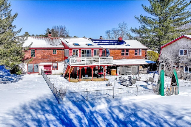 snow covered property with stairway, a chimney, fence, and a wooden deck