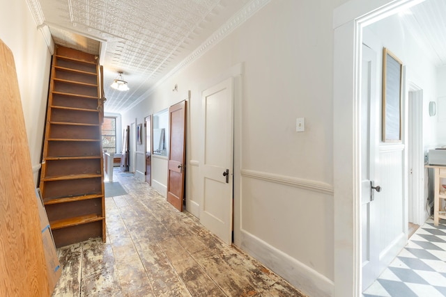 hallway featuring an ornate ceiling, crown molding, baseboards, and stairs