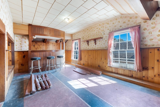 interior space with a wainscoted wall, wooden walls, plenty of natural light, and wallpapered walls