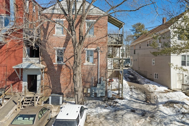 snow covered house featuring brick siding