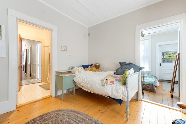 bedroom featuring ornamental molding, lofted ceiling, and light wood finished floors