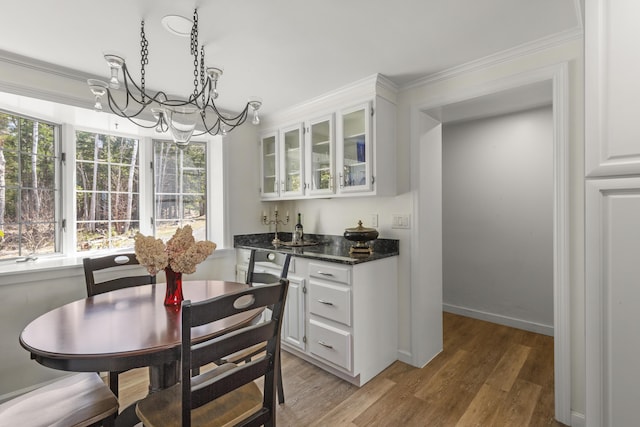825 Hendricks Hill Rd, Southport, ME 04576 - dining area featuring a chandelier, bar with sink, light wood-type flooring, and crown molding