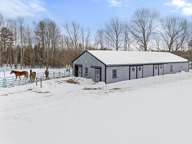 snow covered structure with an outbuilding, a pole building, and fence