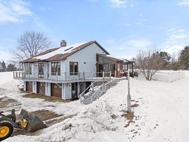 snow covered property with a chimney, a wooden deck, and stairs