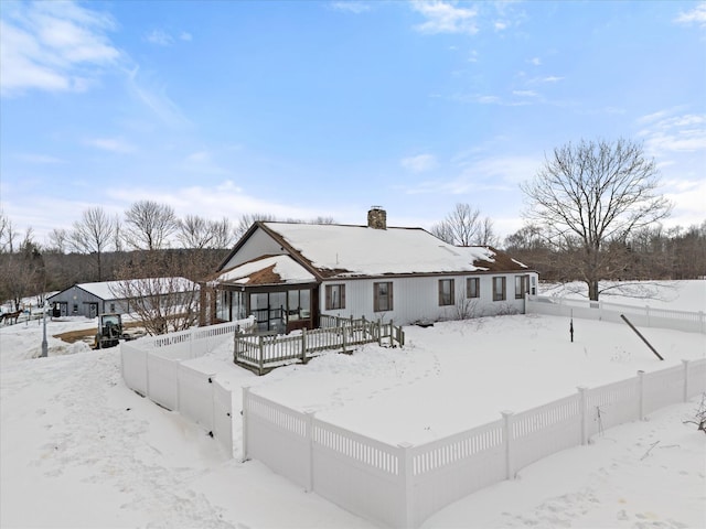 snow covered back of property with a gazebo, a chimney, and a fenced backyard