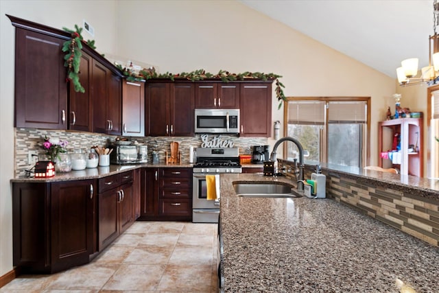 kitchen featuring stainless steel appliances, dark stone countertops, a sink, and decorative backsplash